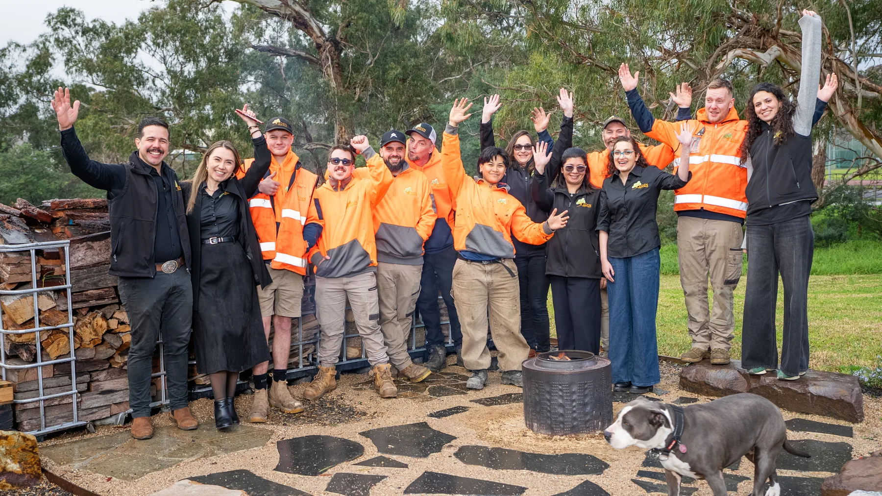 The Eden Building & Landscaping team with hands raised around the fire pit at the yard